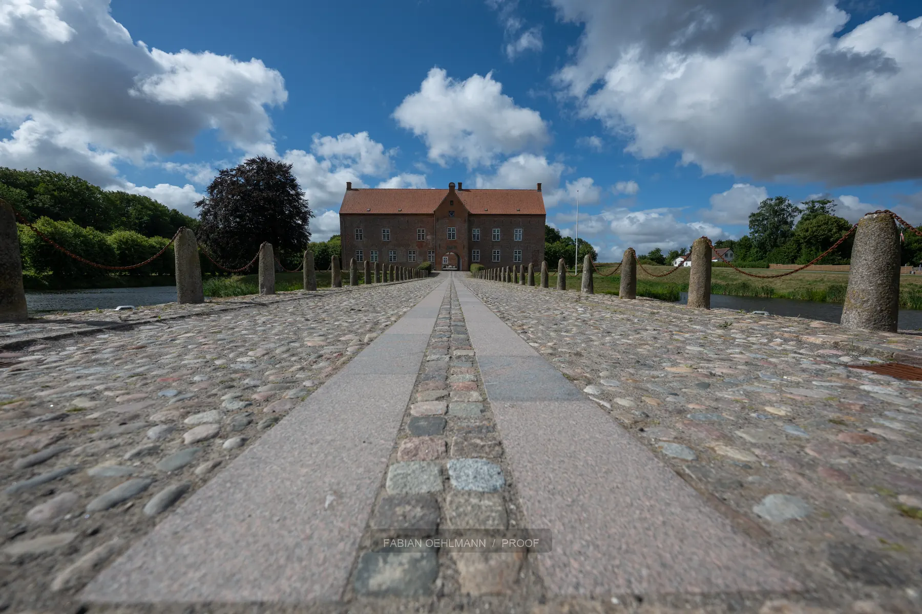 Stone road leading toward a historic building under dramatic clouds