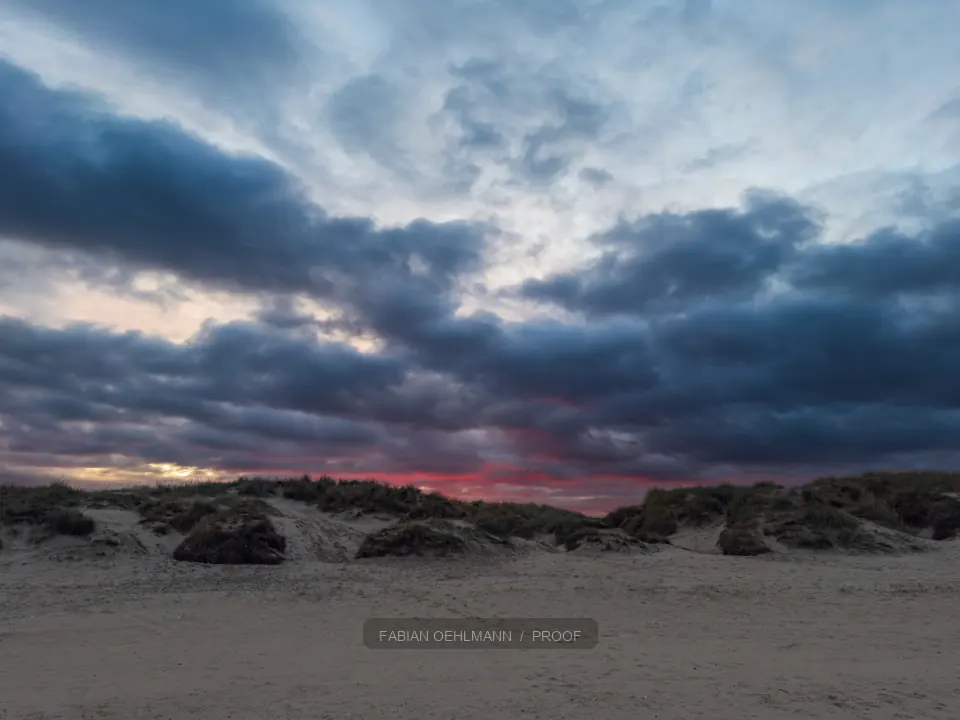Storm clouds catching red light above a beach